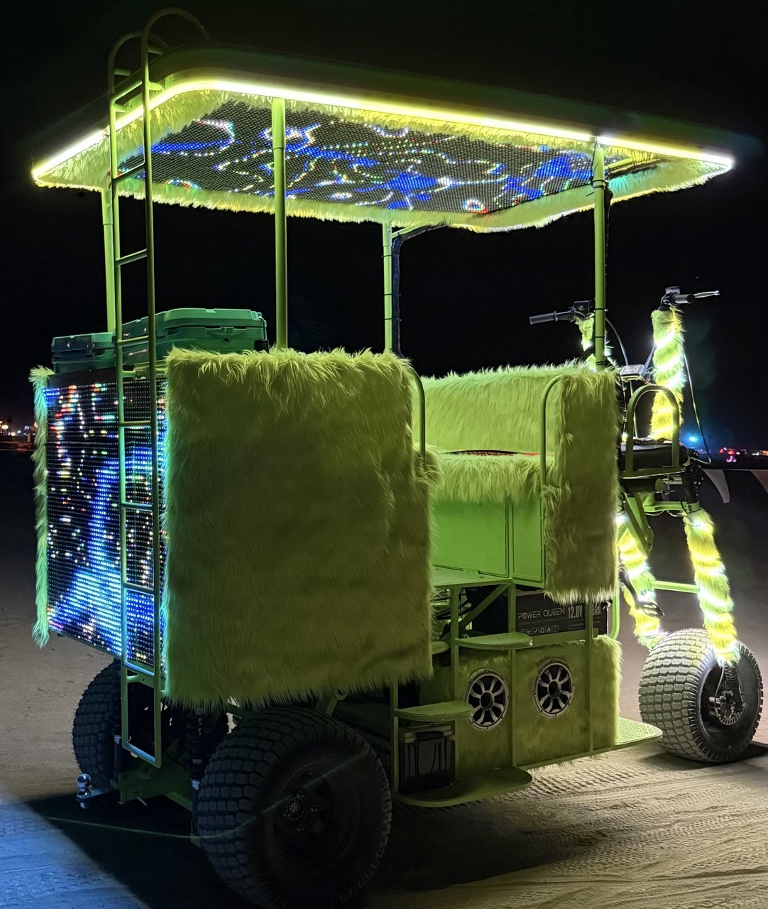 Lime green custom electric chariot with LED screen panels lit up at night