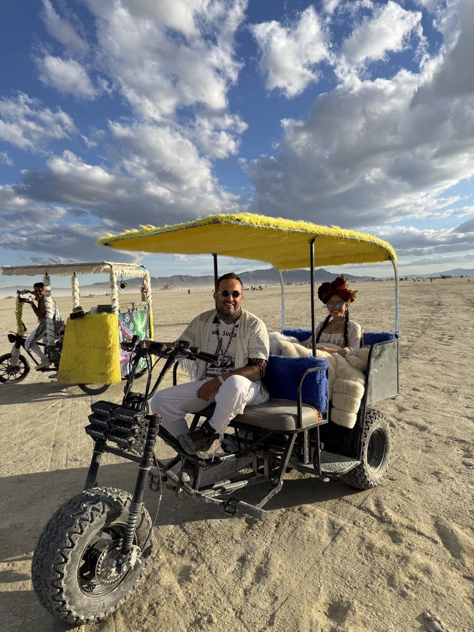 Ali Horuz driving a custom electric trike with a yellow canopy across the desert