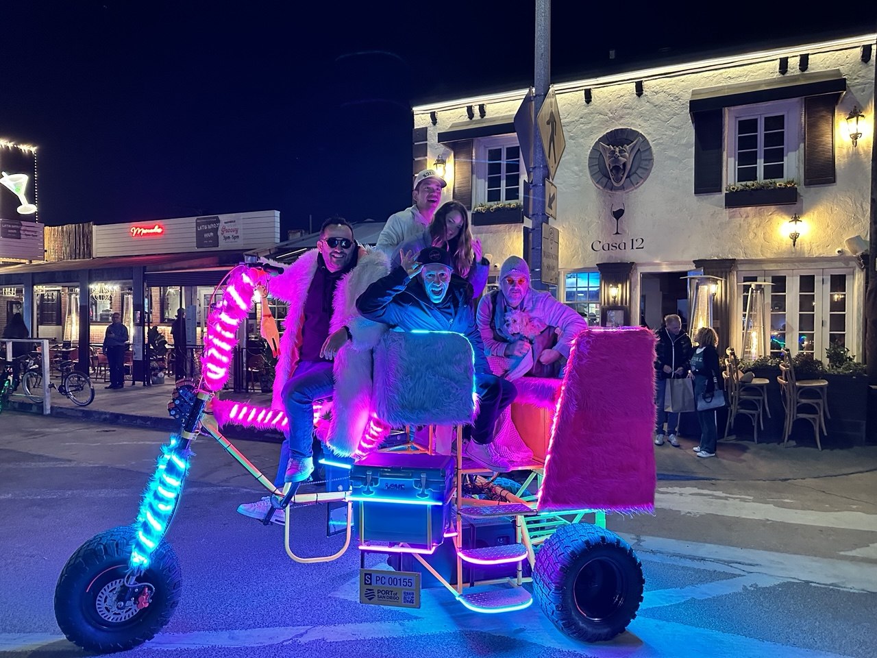 Ali Horuz and riders on a custom pink LED pedicab at night in San Diego